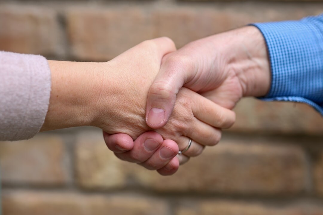 Two people shaking hands after a source meeting